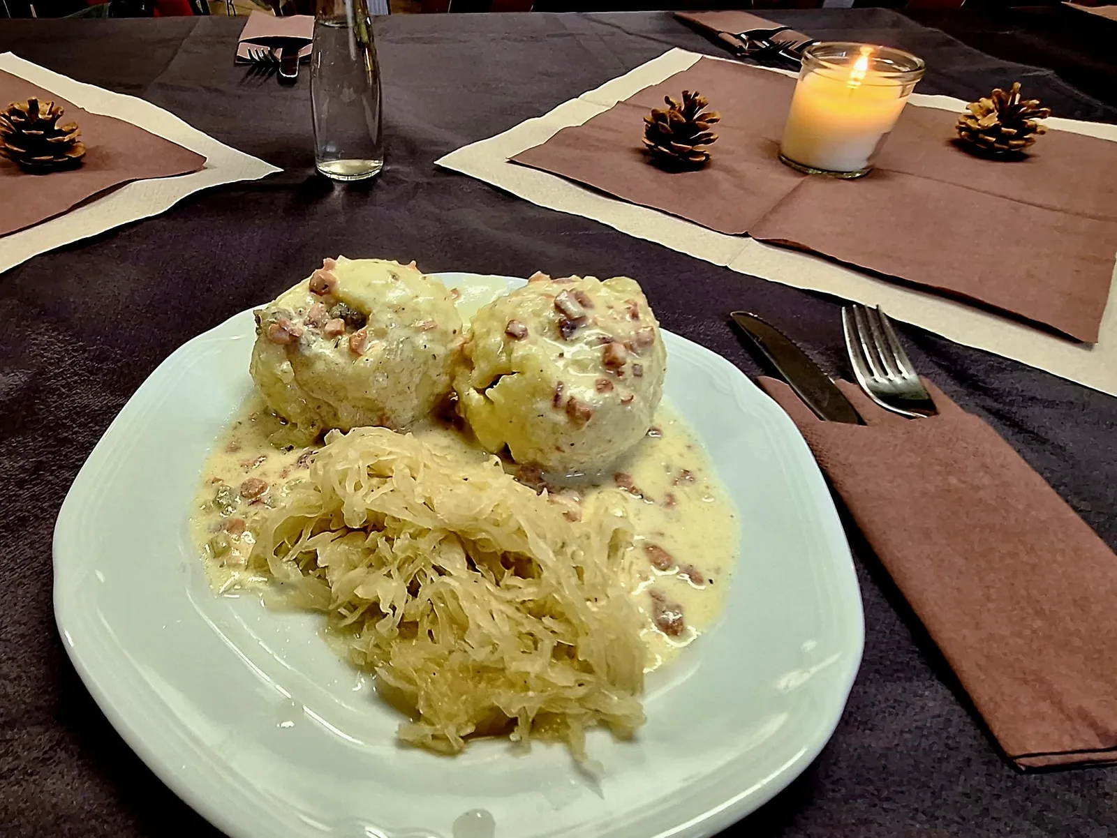 Ein Teller mit Klößen, Soße und Sauerkraut auf einem gedeckten Tisch.