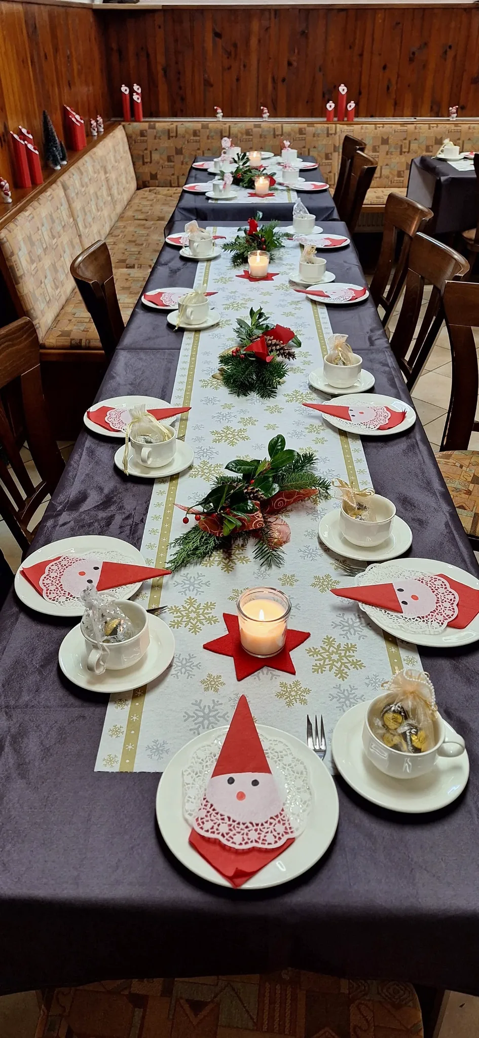 Lange Tafel mit Tannengrün, Kerzen, Tassen und Nikolausservietten.