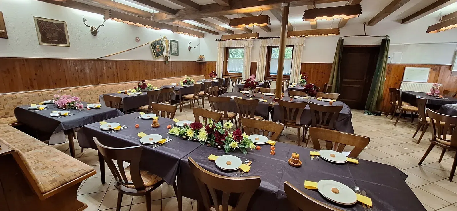 Der Saal des Kreuzberghauses mit gedeckten Tischen, Blumen und herbstlicher Dekoration.