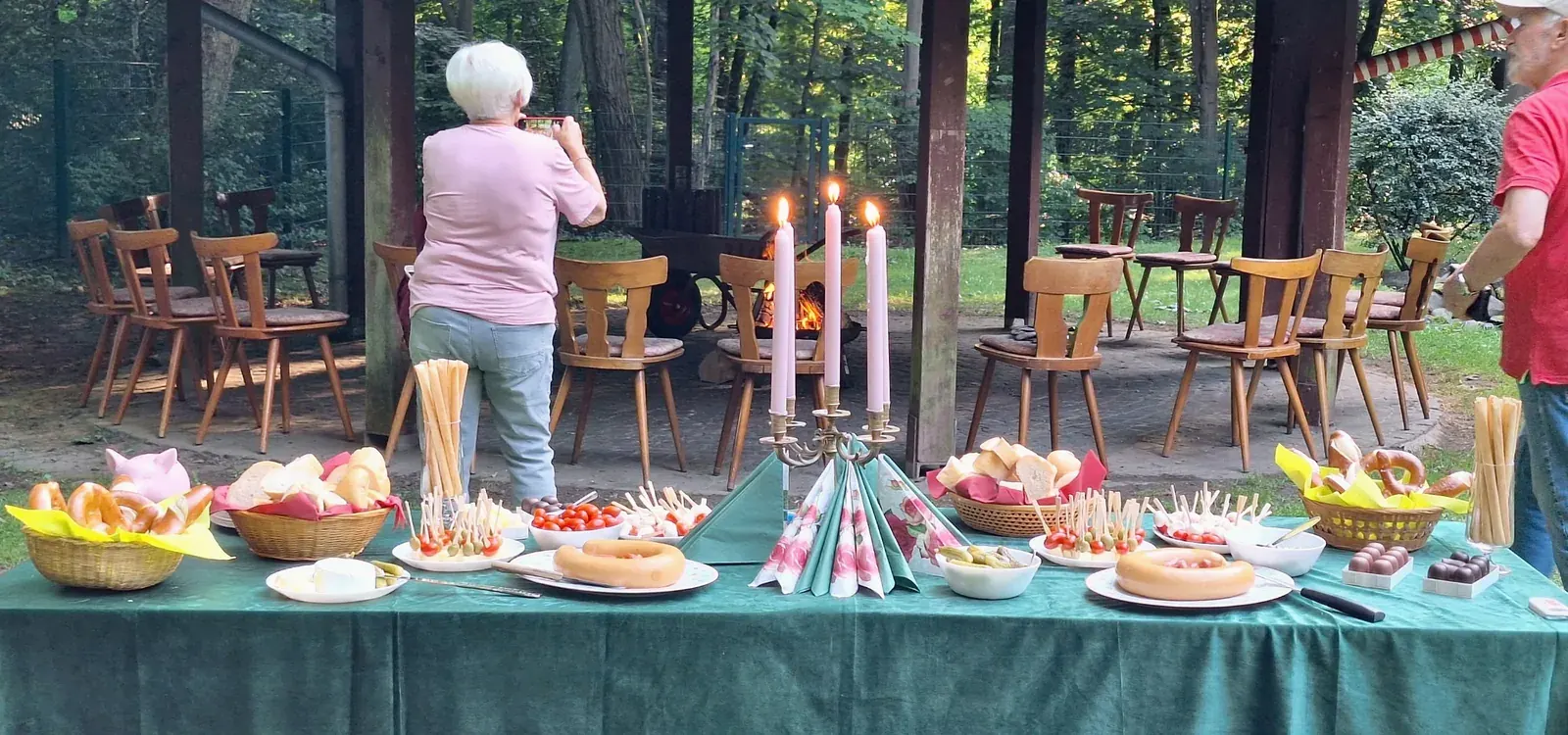 Brot, Brezeln und kleine Speisen auf einem gedeckten Tisch vor dem Grillpavillon.
