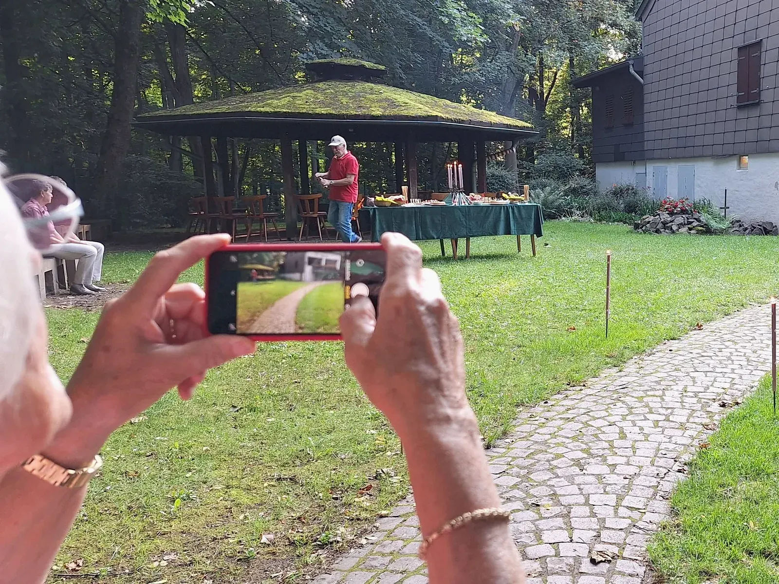 Eine Besucherin fotografiert mit ihrem Smartphone die Feier am Grillpavillon.