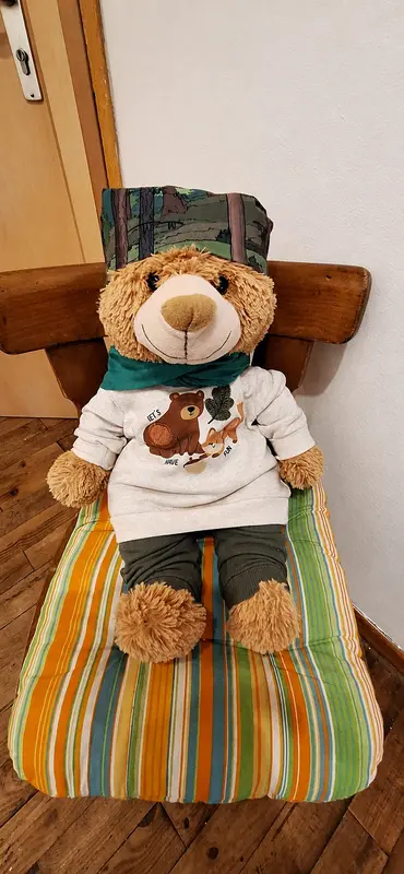 Maskottchen Waldi sitzt auf einem gestreiften Polster in der Familienoase