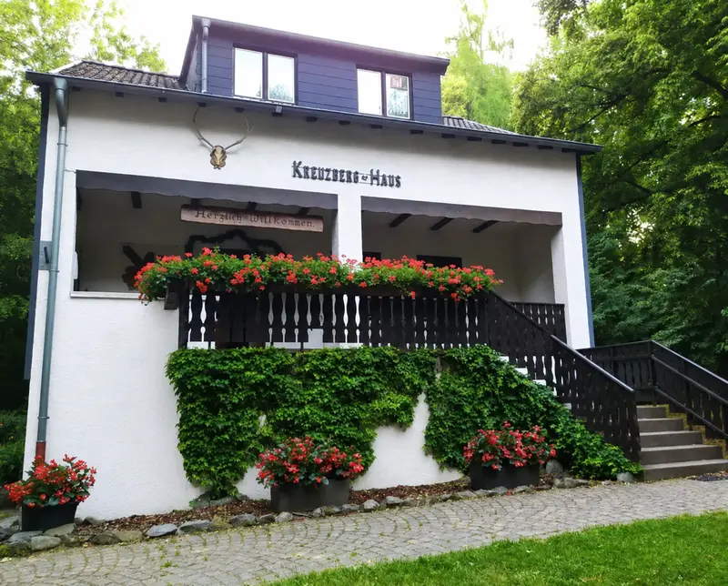 Das vollständig sichtbare Kreuzberghaus in Völklingen mit Dachgauben, Terrasse und Waldumgebung