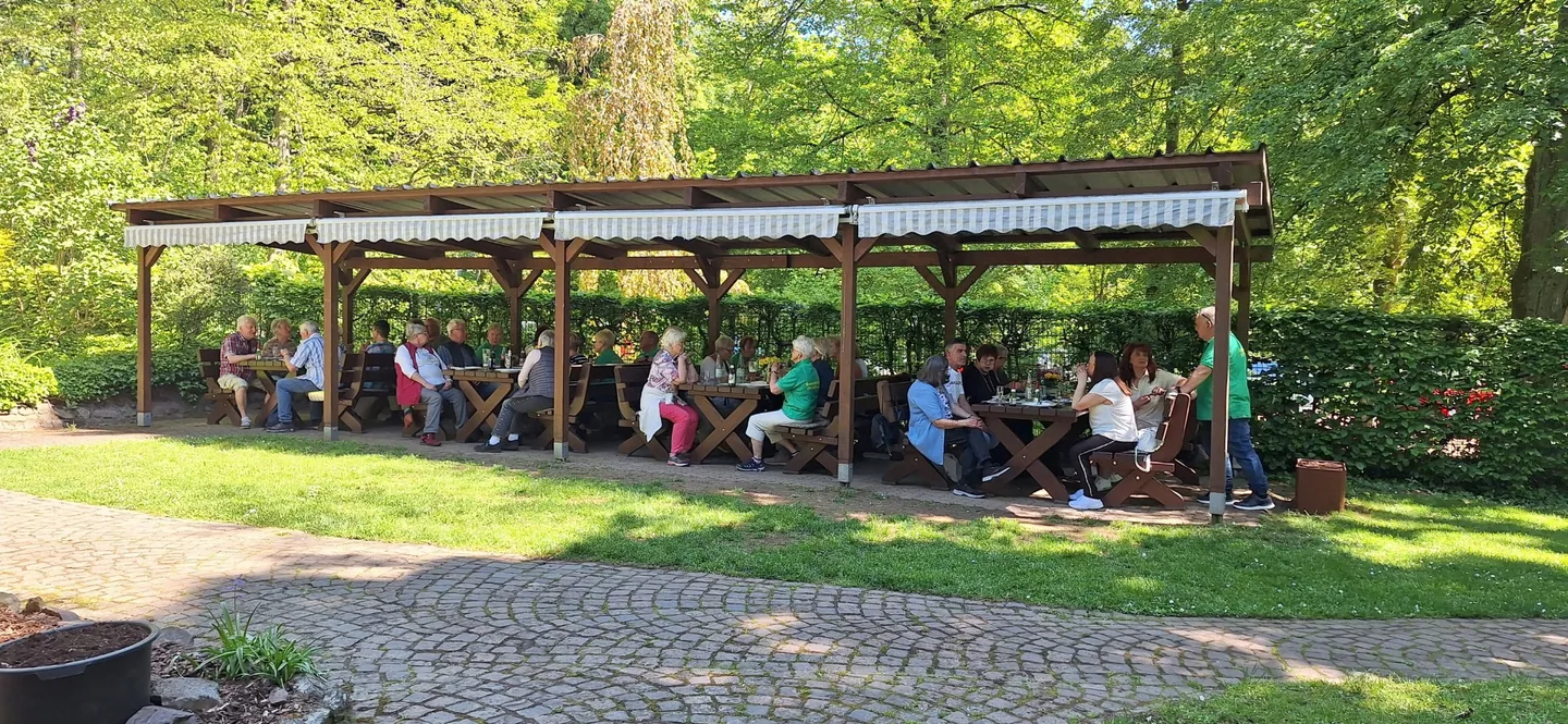 Vereinsmitglieder sitzen unter der überdachten Terrasse am Kreuzberghaus